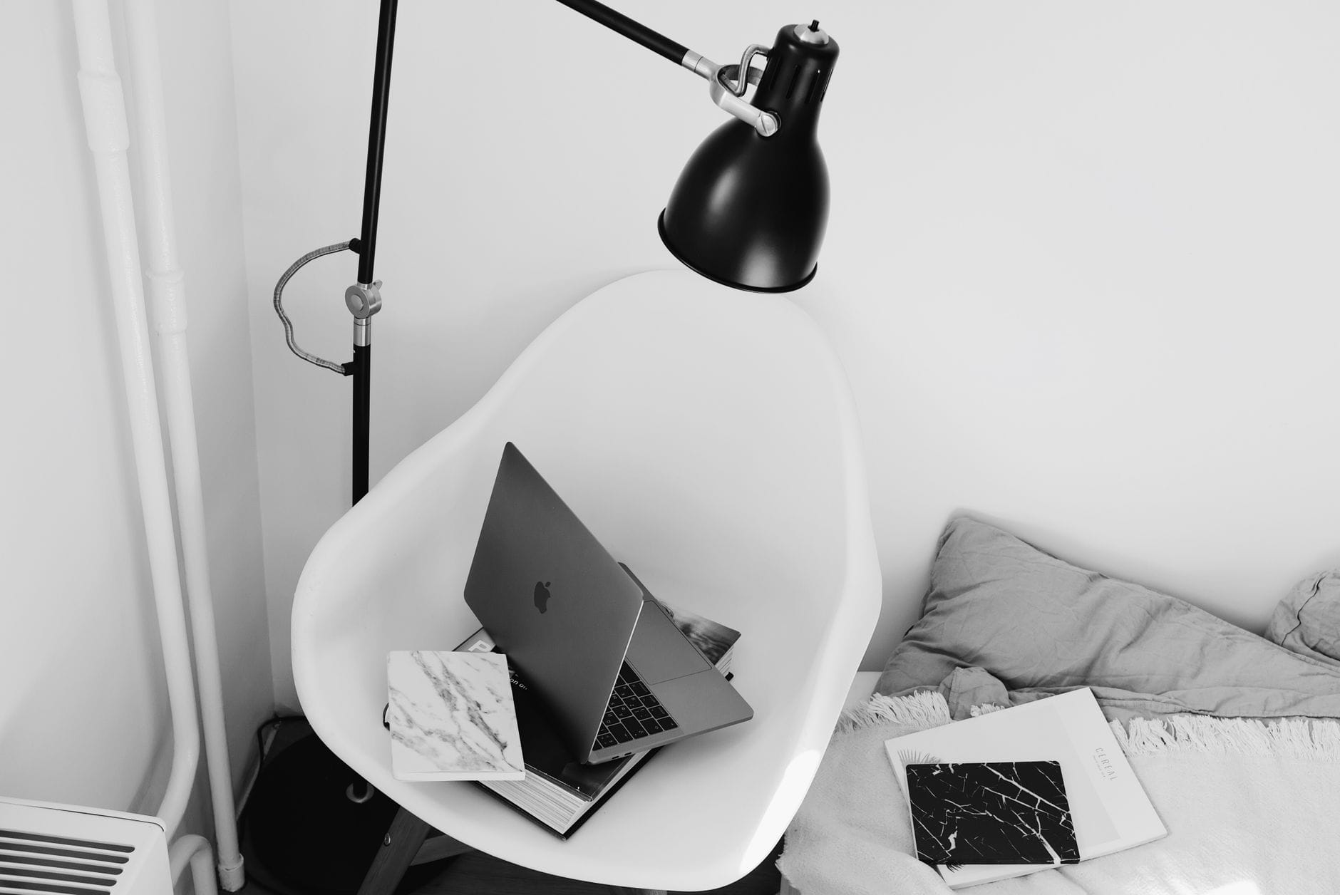 Drewniany fotel z laptopem pod lampą w jasnym, domowym kąciku pracy