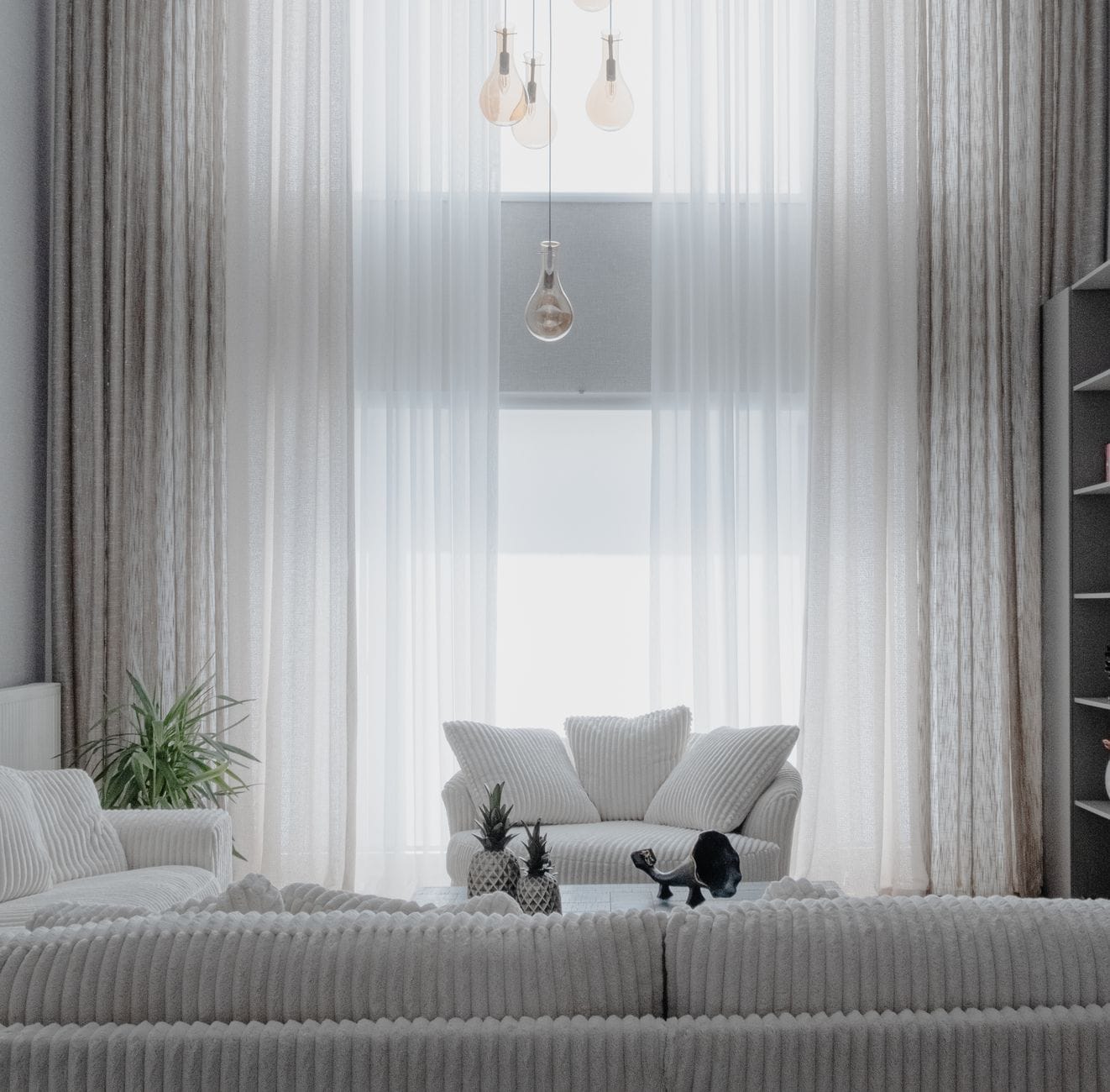 Minimalistyczny salon z jasnymi sofami i zasłonami w miękkim świetle