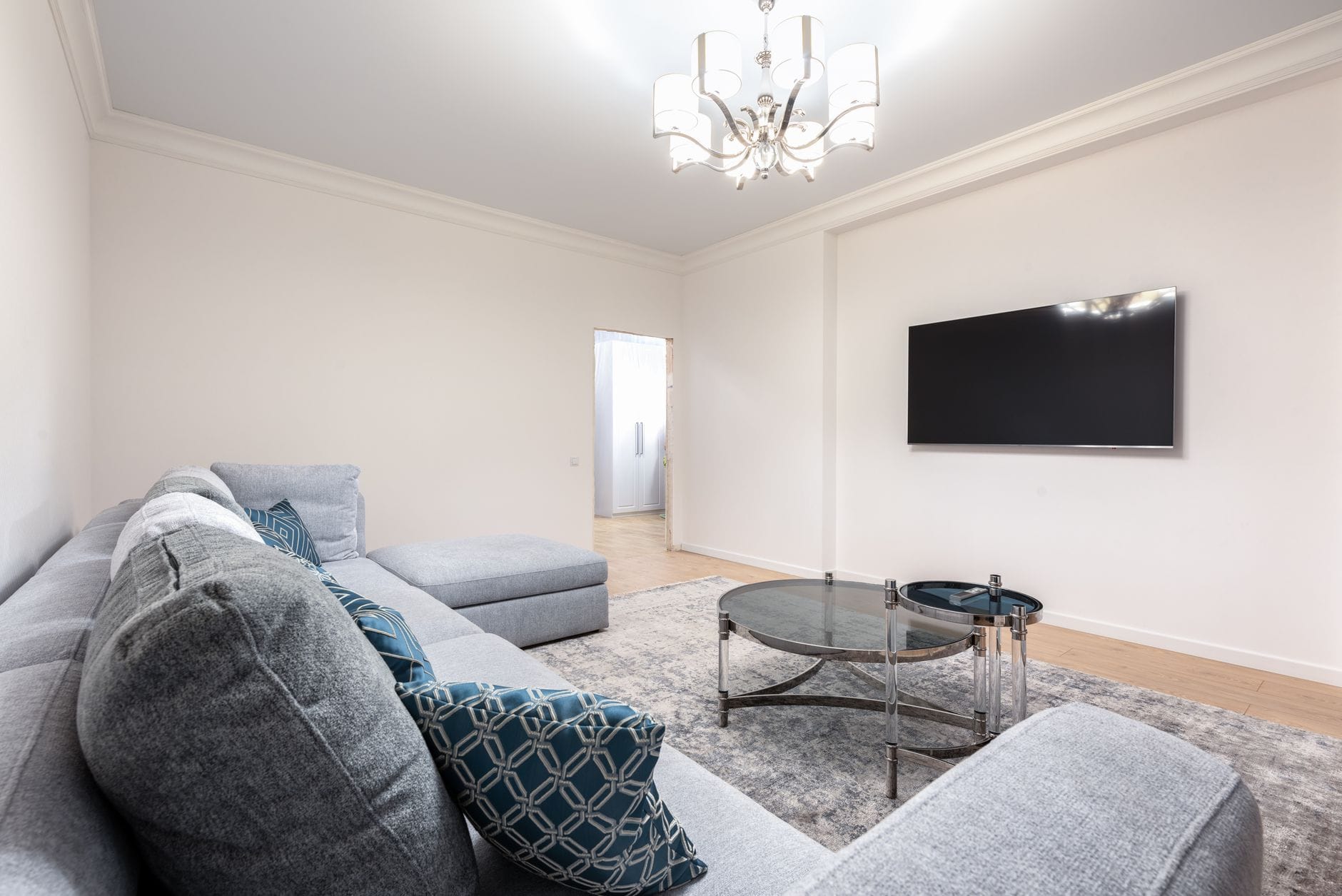 Nowoczesny salon z kanapą, telewizorem i żyrandolem nad stołami