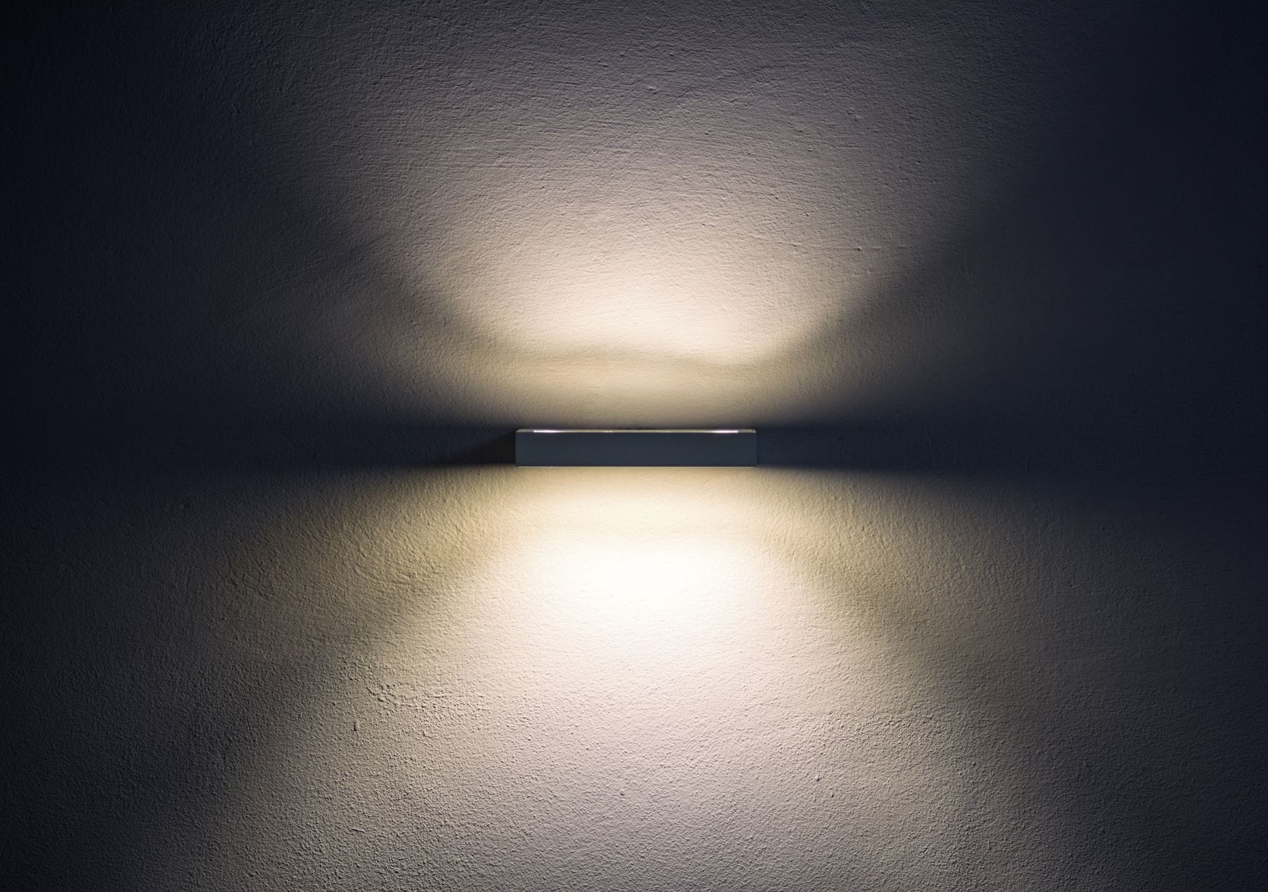 Minimalistyczna kinkietowa lampa LED rzucająca miękkie cienie na ścianę